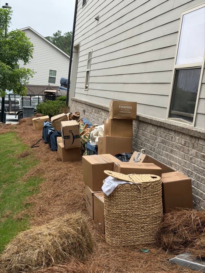 Boxes and bins staged curbside for pickup along a home's exterior