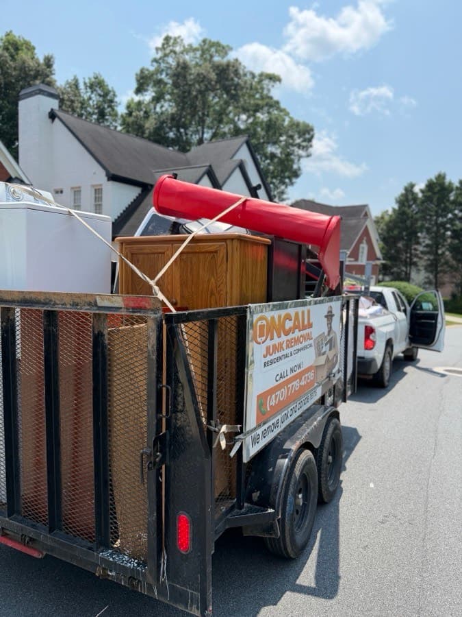 OnCall trailer loaded with a dresser, appliances, and furniture curbside after a residential pickup